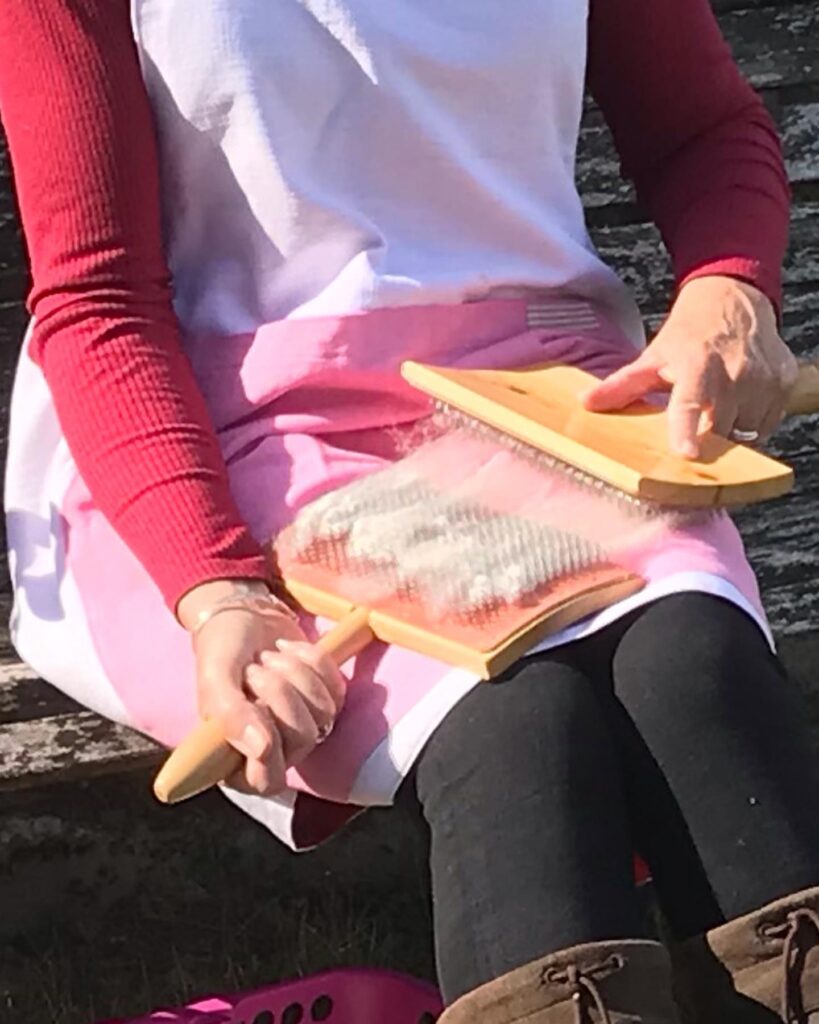 Client carding wool, knees protected by strong patch on pinny