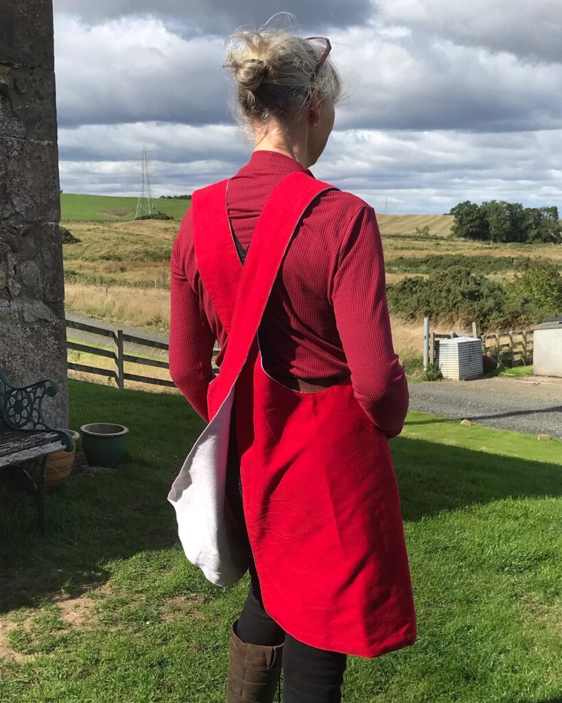 A friend wearing her red x-back apron in rural landscape