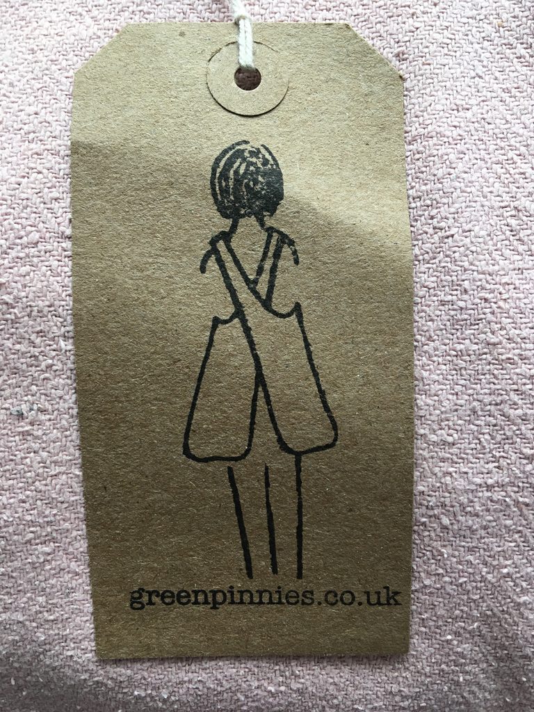 A luggage tag with GreenPinnies logo stamped on it