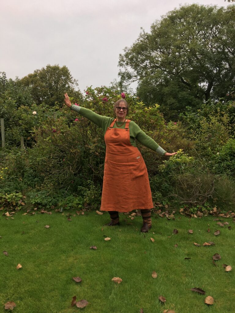 A customer wears her terracotta pinafore dress in the garden