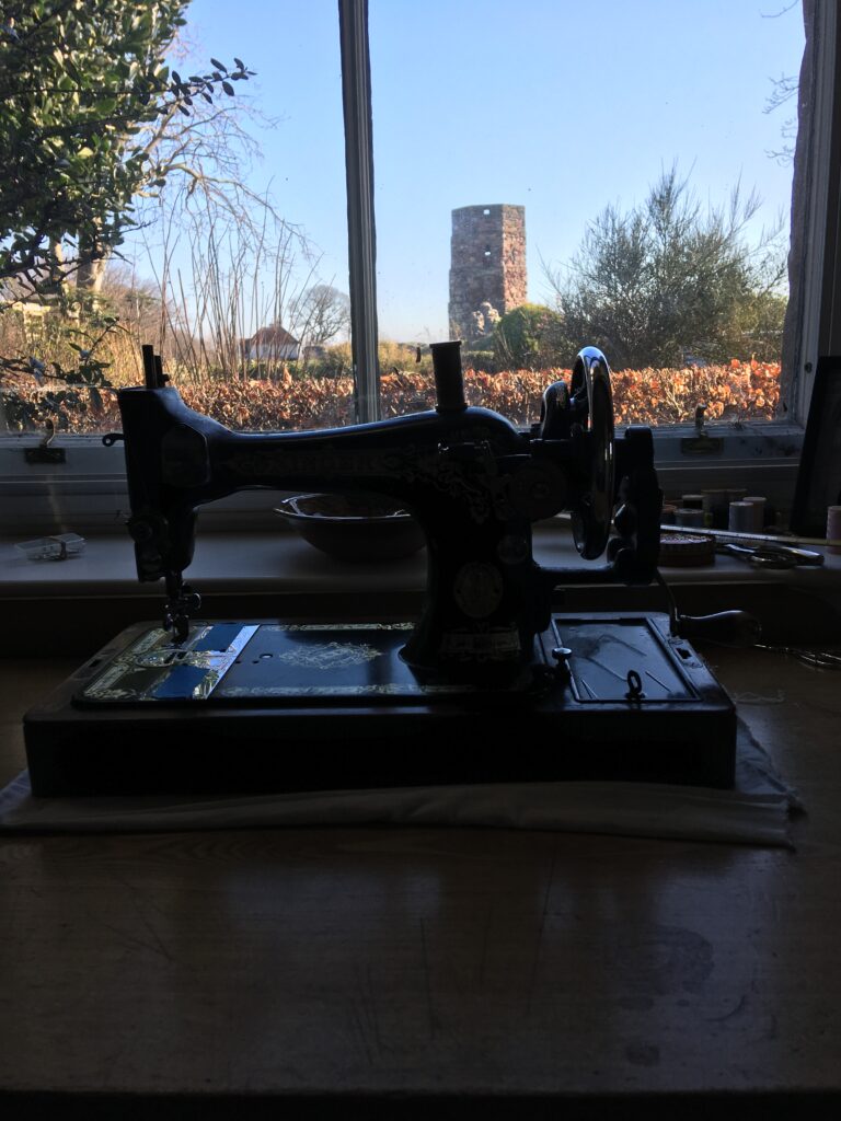 19th Century Singer hand-crank sewing machine, on desk at window with view of Berwick's Bell Tower